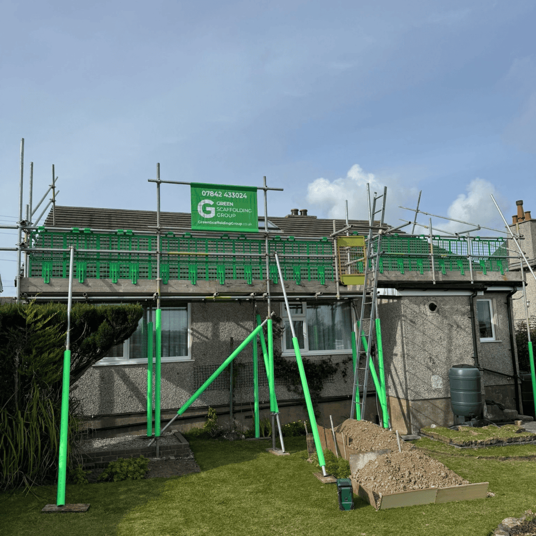 Scaffolding with green safety barriers along the roof of a house