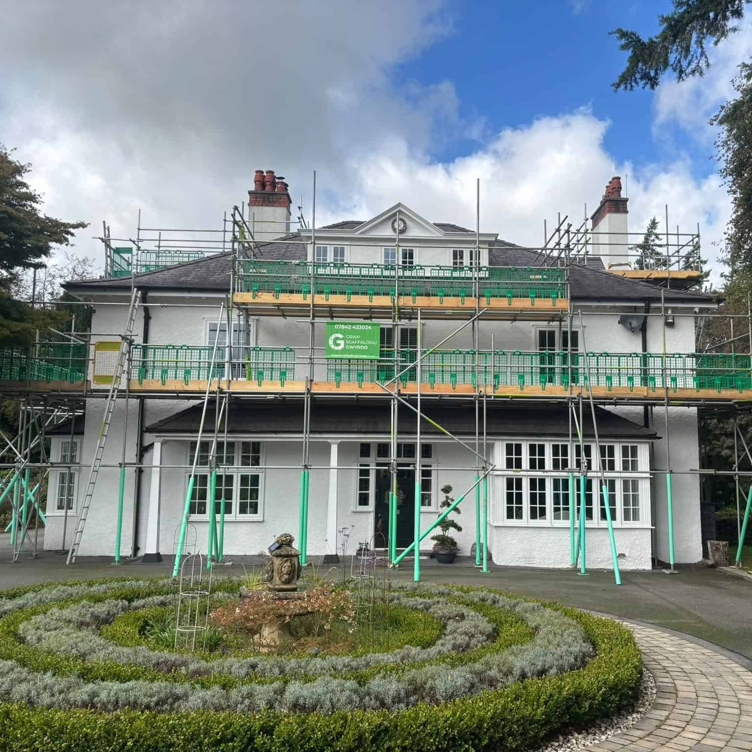 Green scaffolding erected around a house to provide access to the roof