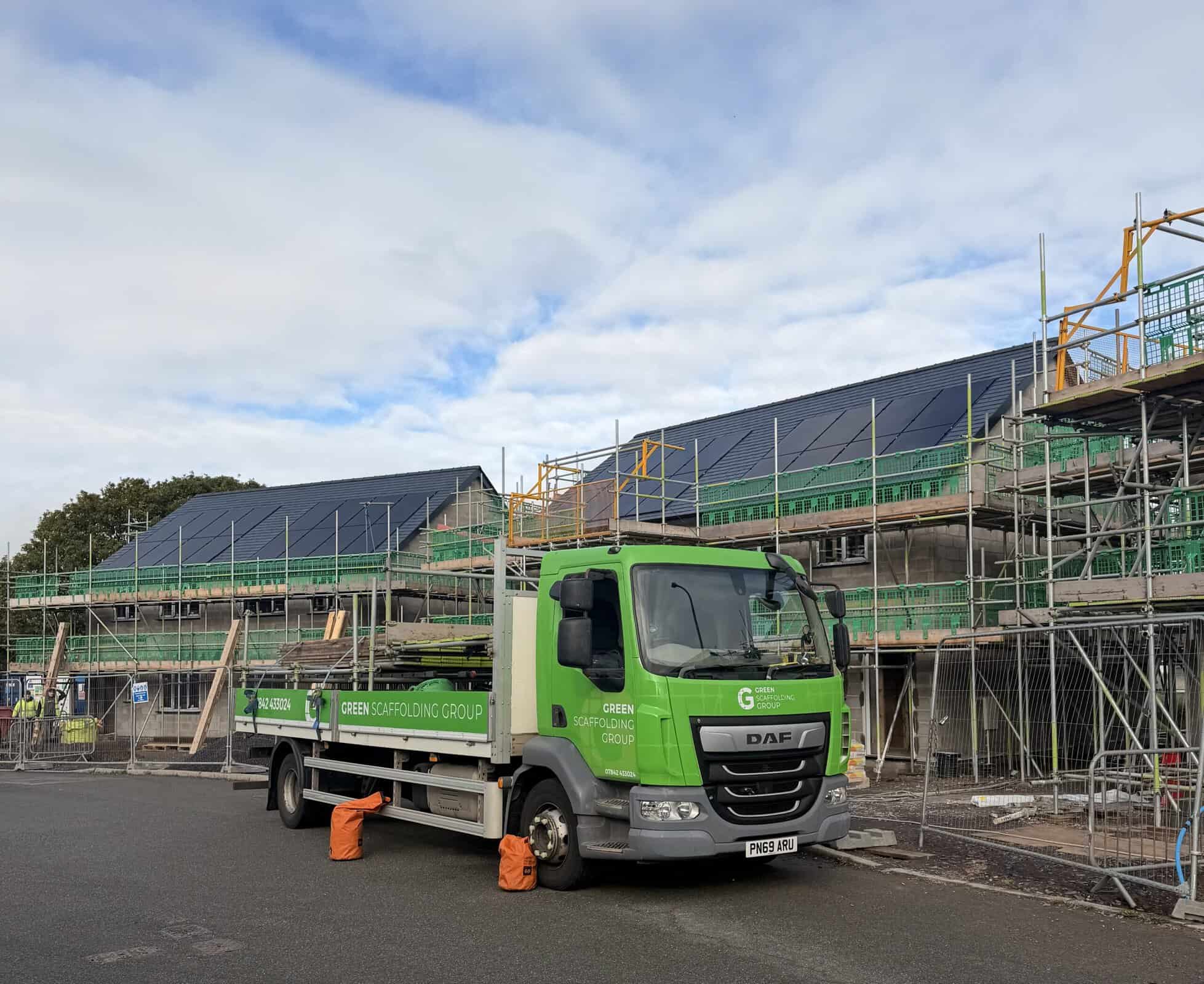 Green Scaffolding Group lorry parked outside a row of houses with scaffolding providing roof access.